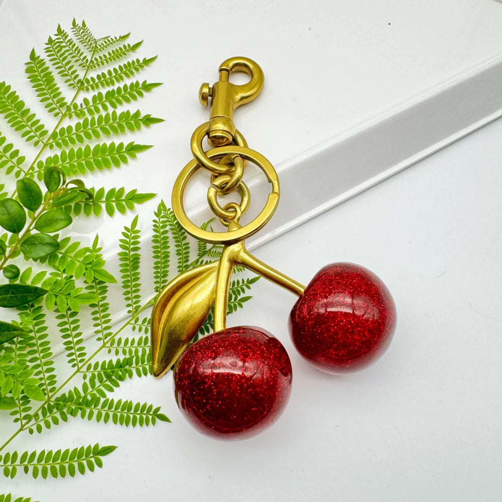 Llavero de cereza roja con charm para bolso y mosquetón dorado en forma de hoja
